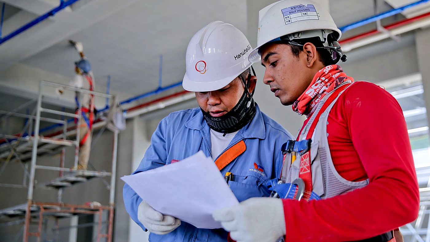 Encargado y recurso preventivo revisando documentación a pie de obra con equipo de protección individual